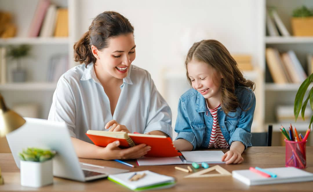 Young girl reading a book with a teacher.