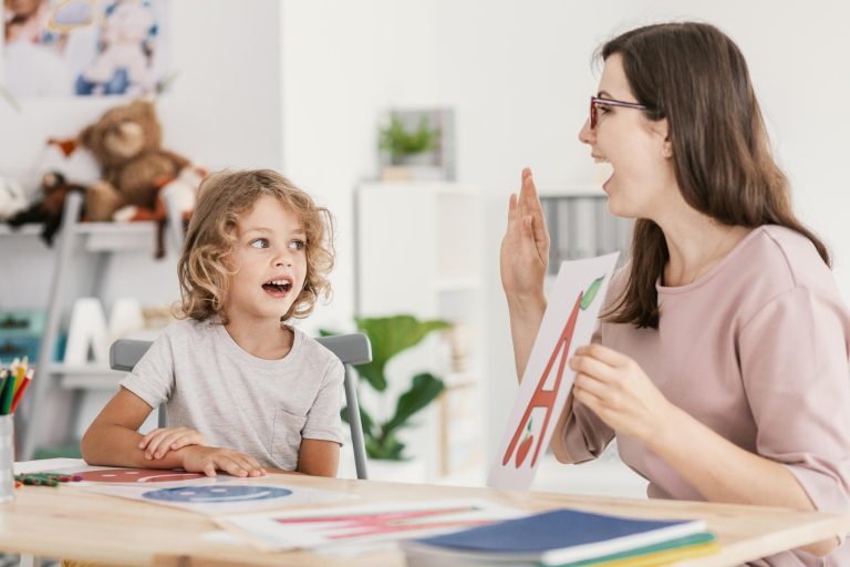 Speech therapist teaching letter pronunciation to a young child.