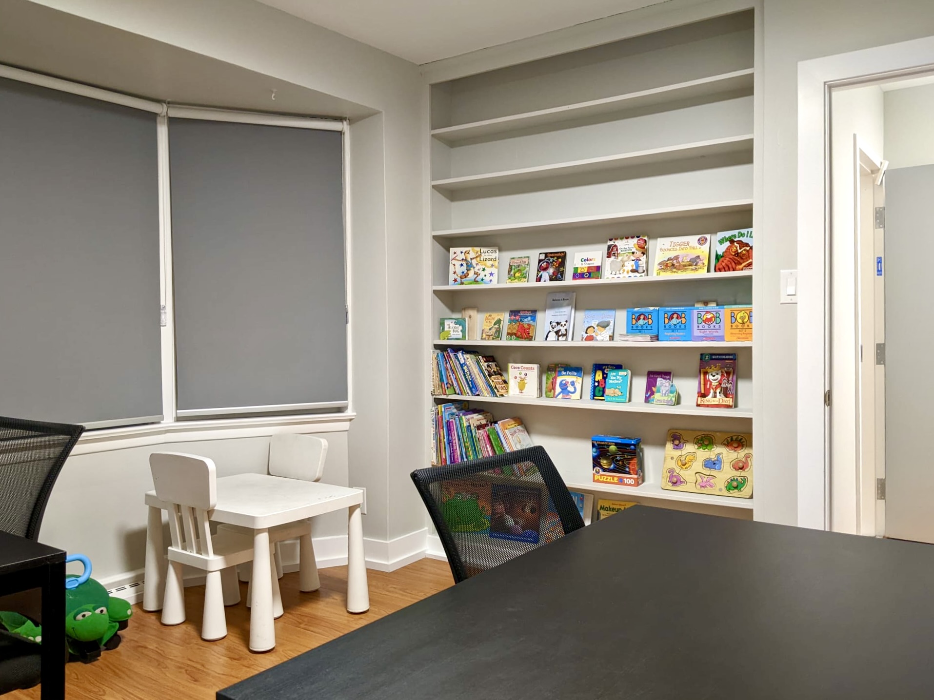 A room with desks and a bookshelf full of books.