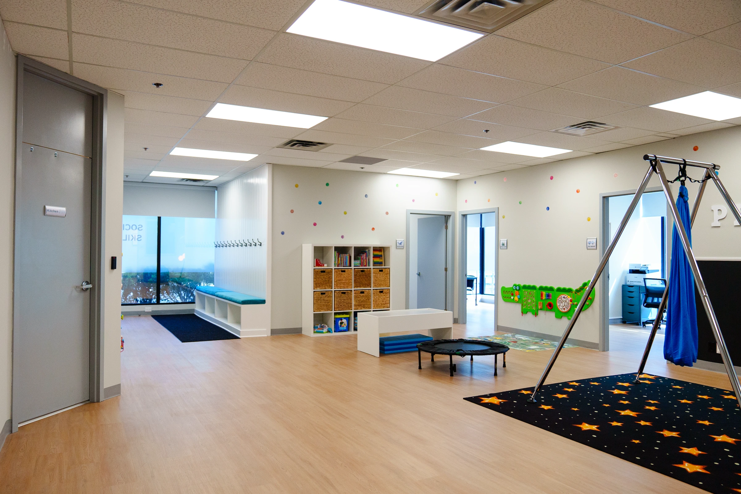 A large playroom with wooden floors, white walls, and toys for children.