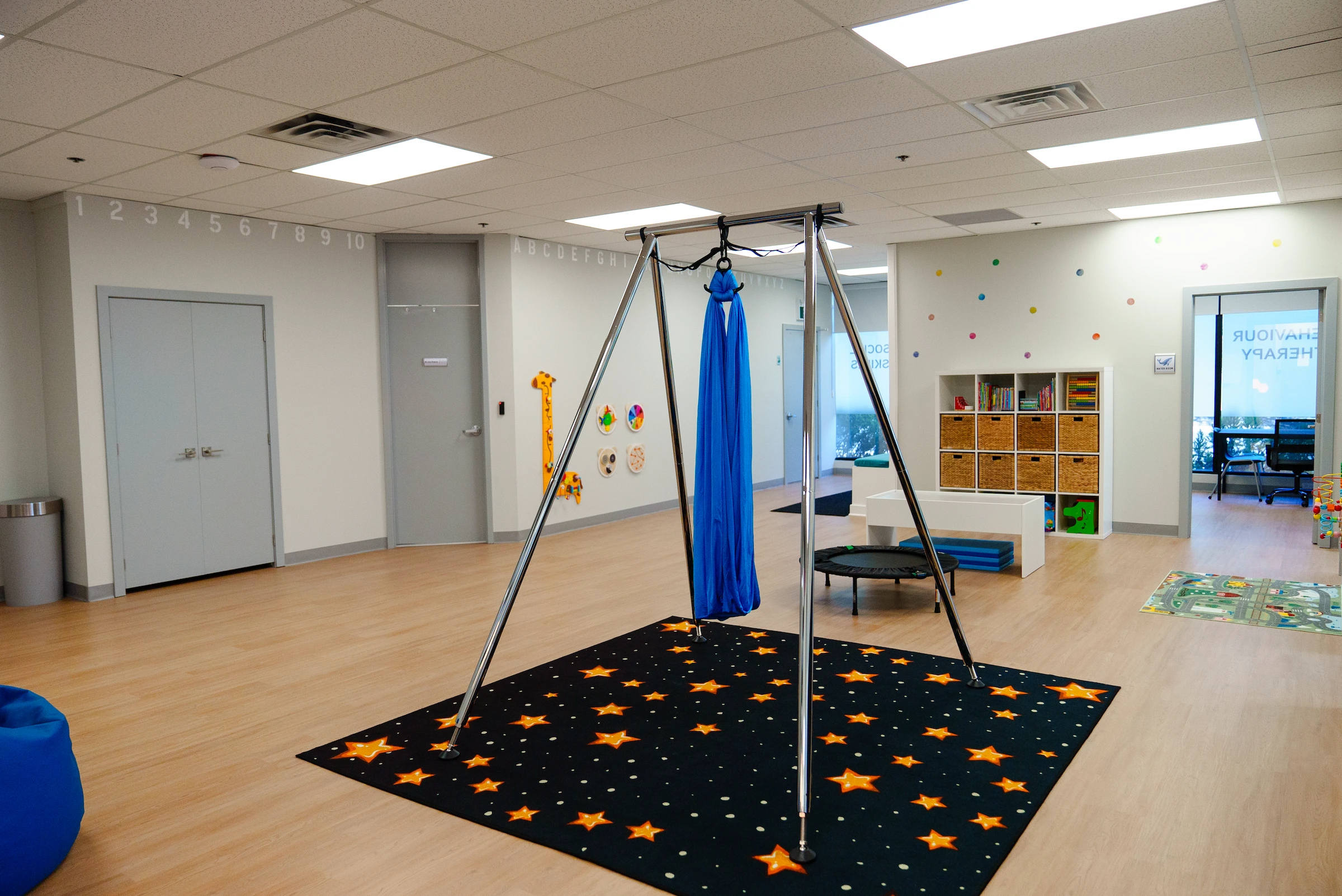 A large playroom with wooden floors, white walls, and a swing.