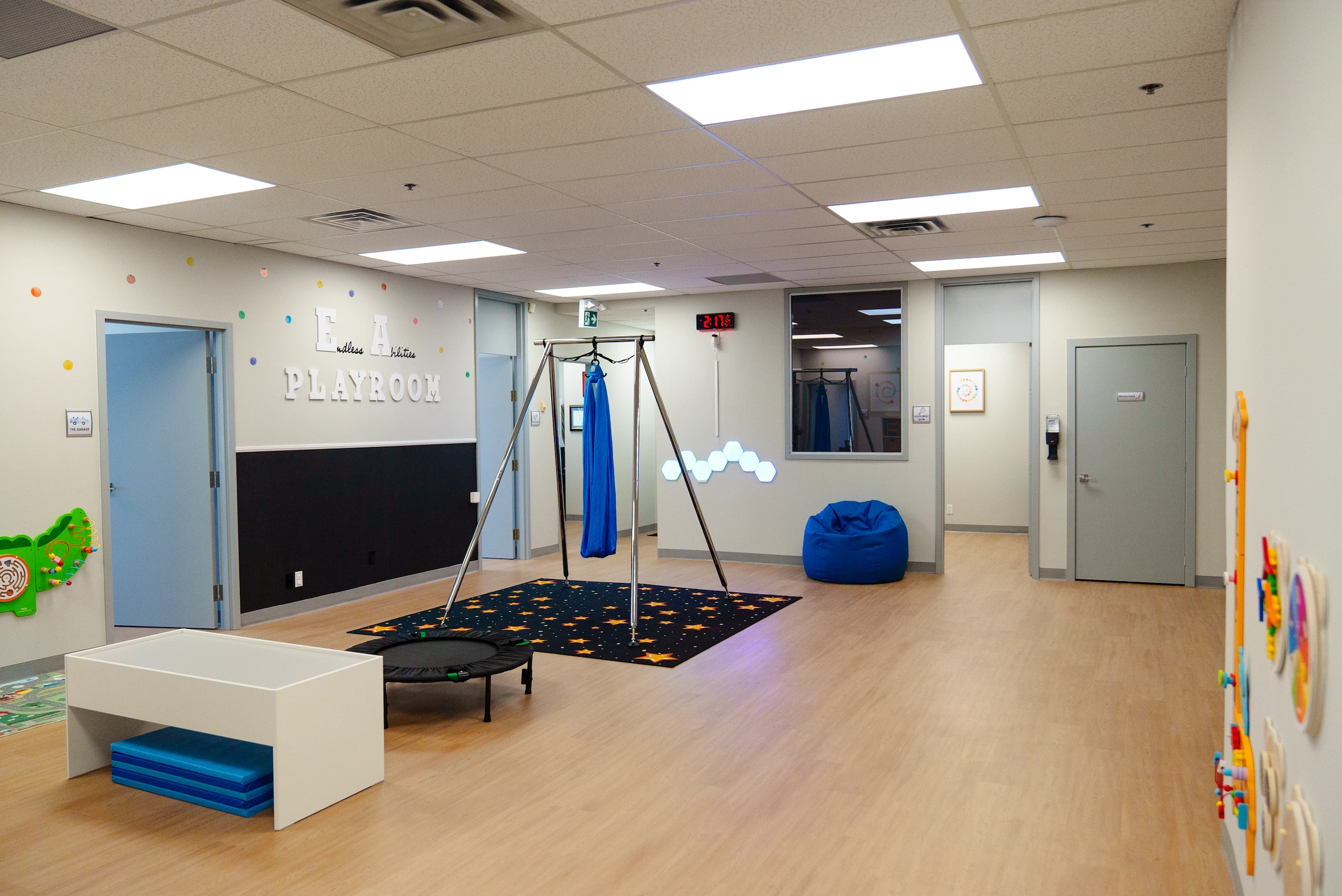 A large playroom with wooden floors, white walls, and learning materials.